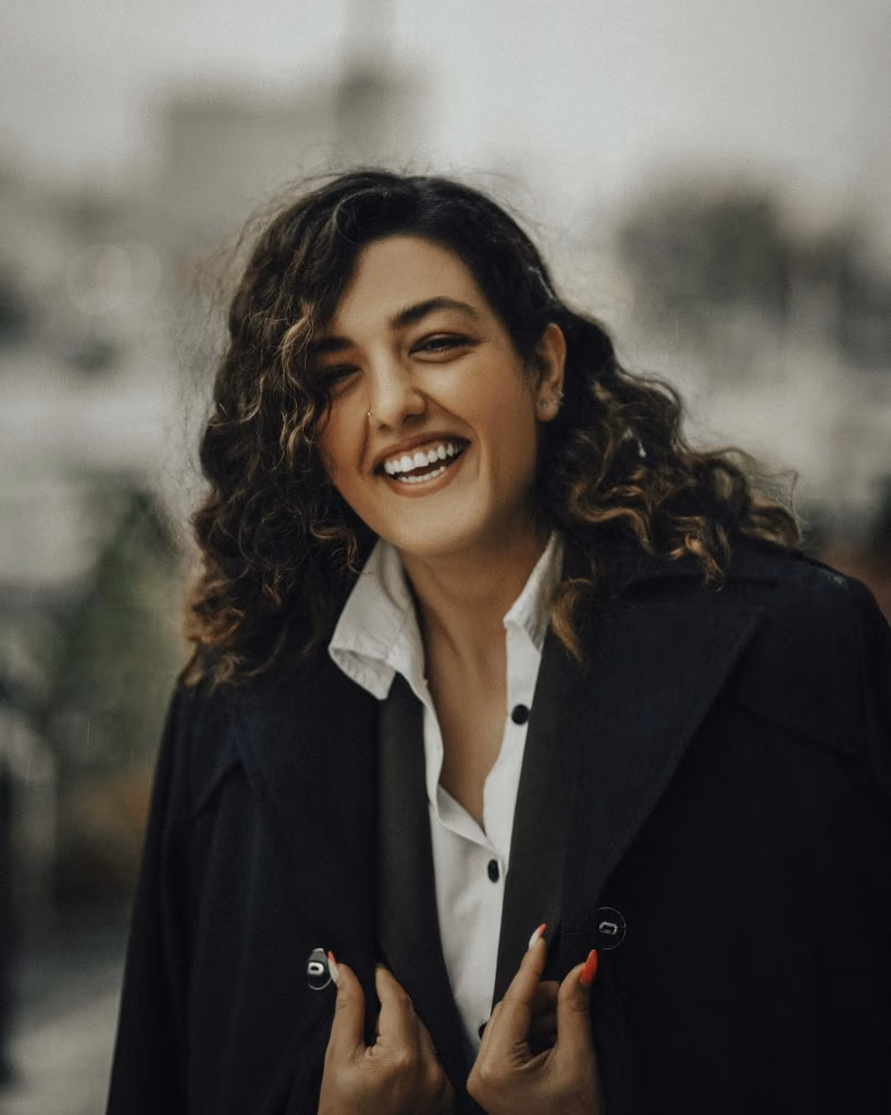 Femme aux cheveux bouclés souriante, veste noire