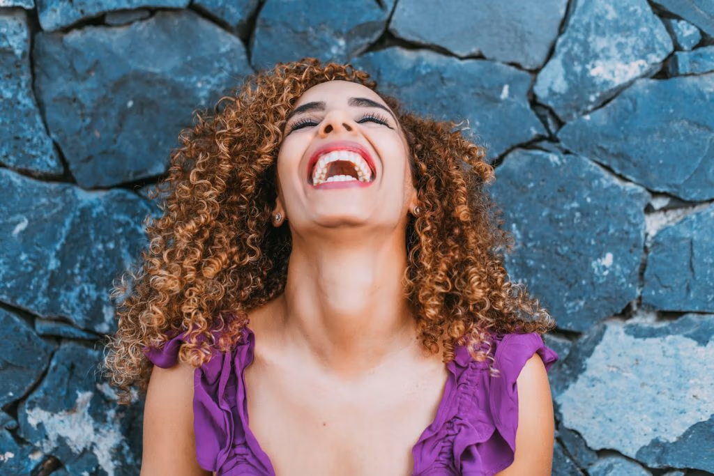 Femme aux cheveux bouclés qui rit